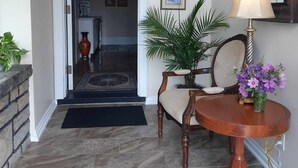 Un pasillo con una silla de madera y una mesa con un jarrón de flores, que conduce a una habitación con una puerta.