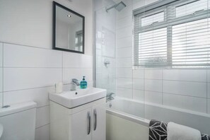 Bathroom features a sink, shower, and window with blinds.