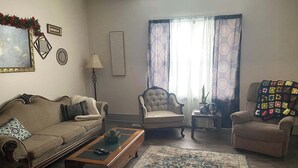 A living room with a sofa, armchair, and a small table with a lamp.