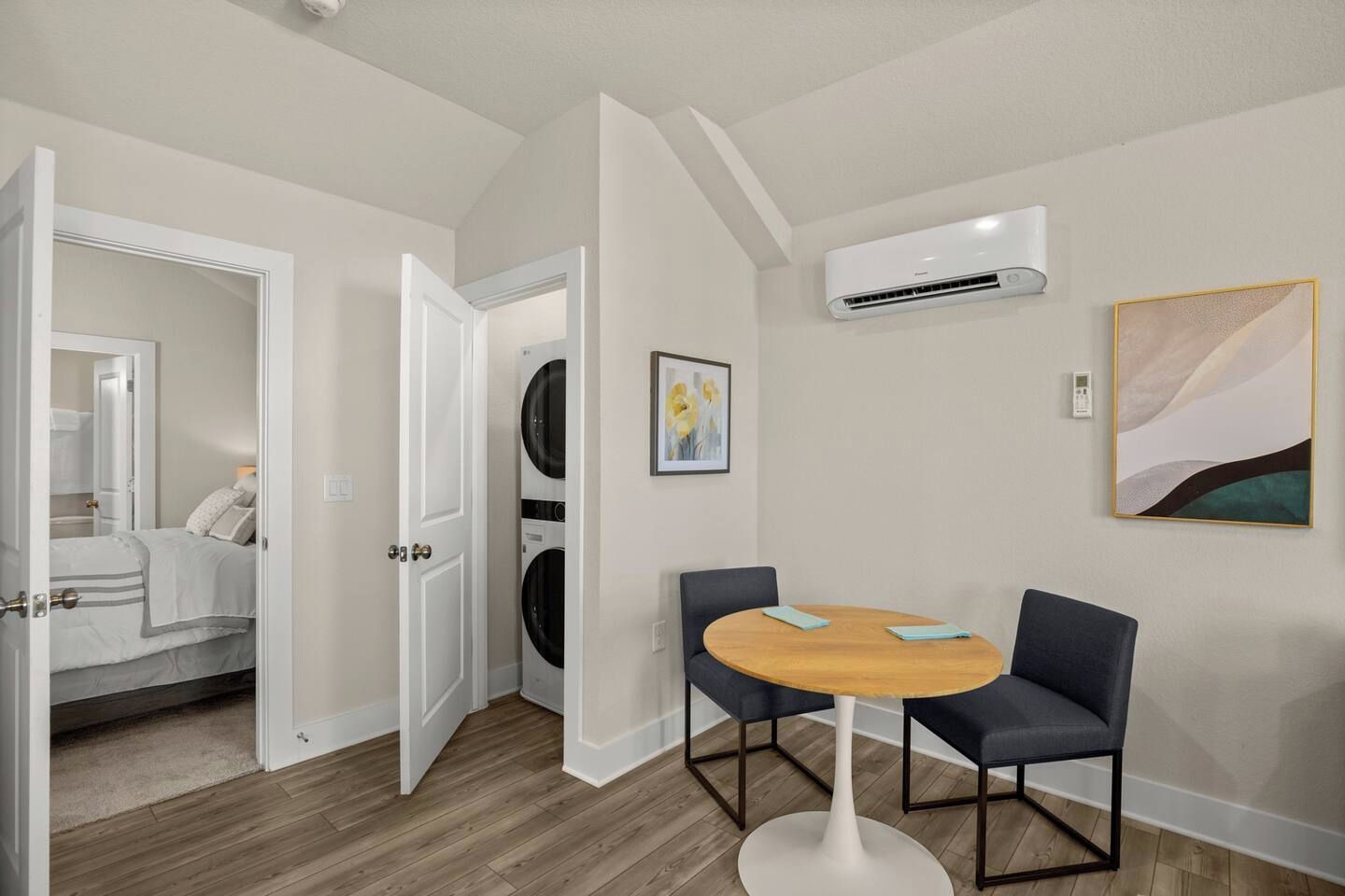 Ein Hotelzimmer mit einem Bett, einer Waschmaschine, einem Esstisch mit Stühlen und einer Klimaanlage.