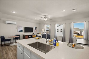 A modern kitchen with a central island, a built-in sink, and a ceiling fan.