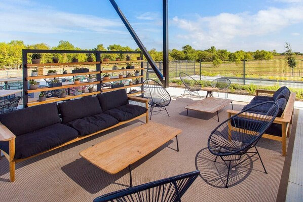 An outdoor seating area with a sofa, chairs, and a table, surrounded by potted plants.