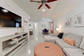 A modern living room with a sofa, a coffee table, a TV, and a ceiling fan.