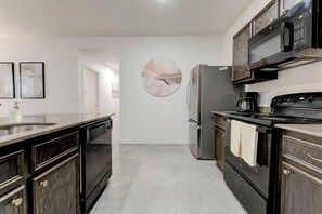 A kitchen with a refrigerator, stove, microwave, and a large circular artwork on the wall. - Your Getaway in Temple (Temple)