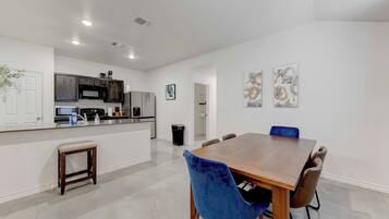 A modern kitchen with built-in appliances, a dining area with a wooden table and chairs, and a clean, white interior.