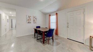 A dining area with a table and chairs, a door, and a hallway. - Your Getaway in Temple (Temple)