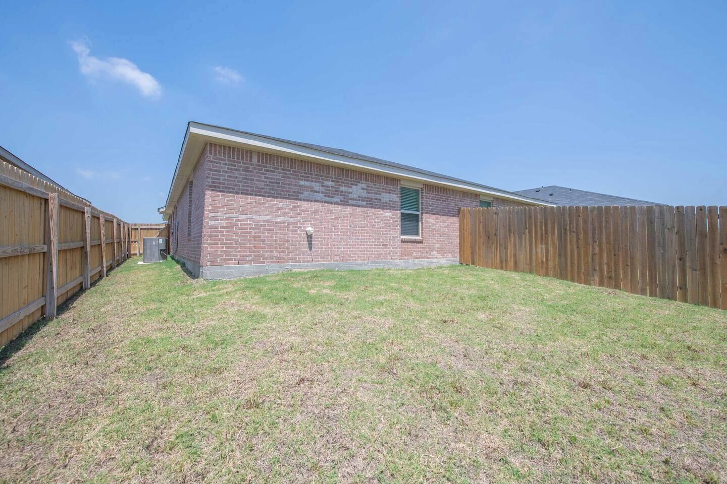 A single-story brick building with a fenced backyard.