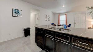 A modern kitchen with a marble countertop, stainless steel sink, and dark wooden cabinets. - Your Getaway in Temple (Temple)