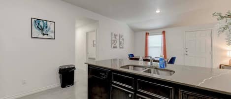 Una cocina moderna con encimera de mármol, pileta de acero inoxidable y alacenas de madera oscura.