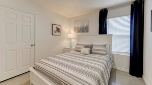 A bedroom with a bed, bedside tables, a door, a window with curtains, and a wall-mounted artwork. - Your Getaway in Temple (Temple)