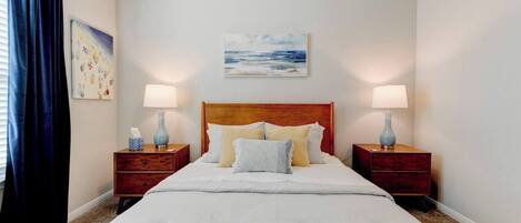 Habitación de hotel con una cama grande, dos mesitas de noche con lámparas, un cabecero y un cuadro en la pared.