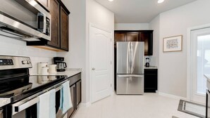 A modern kitchen with stainless steel appliances, a coffee maker, and a refrigerator. - Spacious 4-Bedroom Retreat in East Temple (Temple)