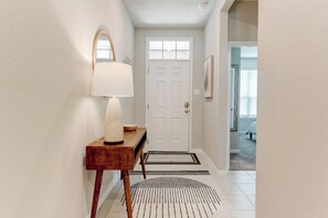 A hallway with a wooden console table, a white lamp, a white door, a black and white rug, and a framed picture on the wall. - Spacious 4-Bedroom Retreat in East Temple (Temple)
