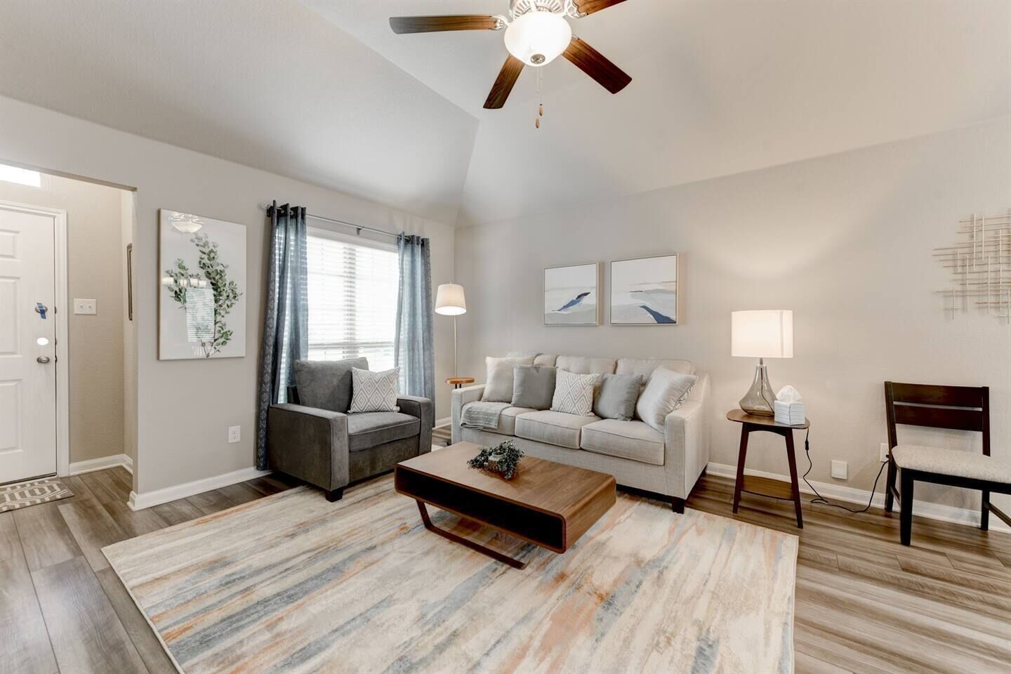 A living room with a ceiling fan, two sofas, a coffee table, and a lamp.
