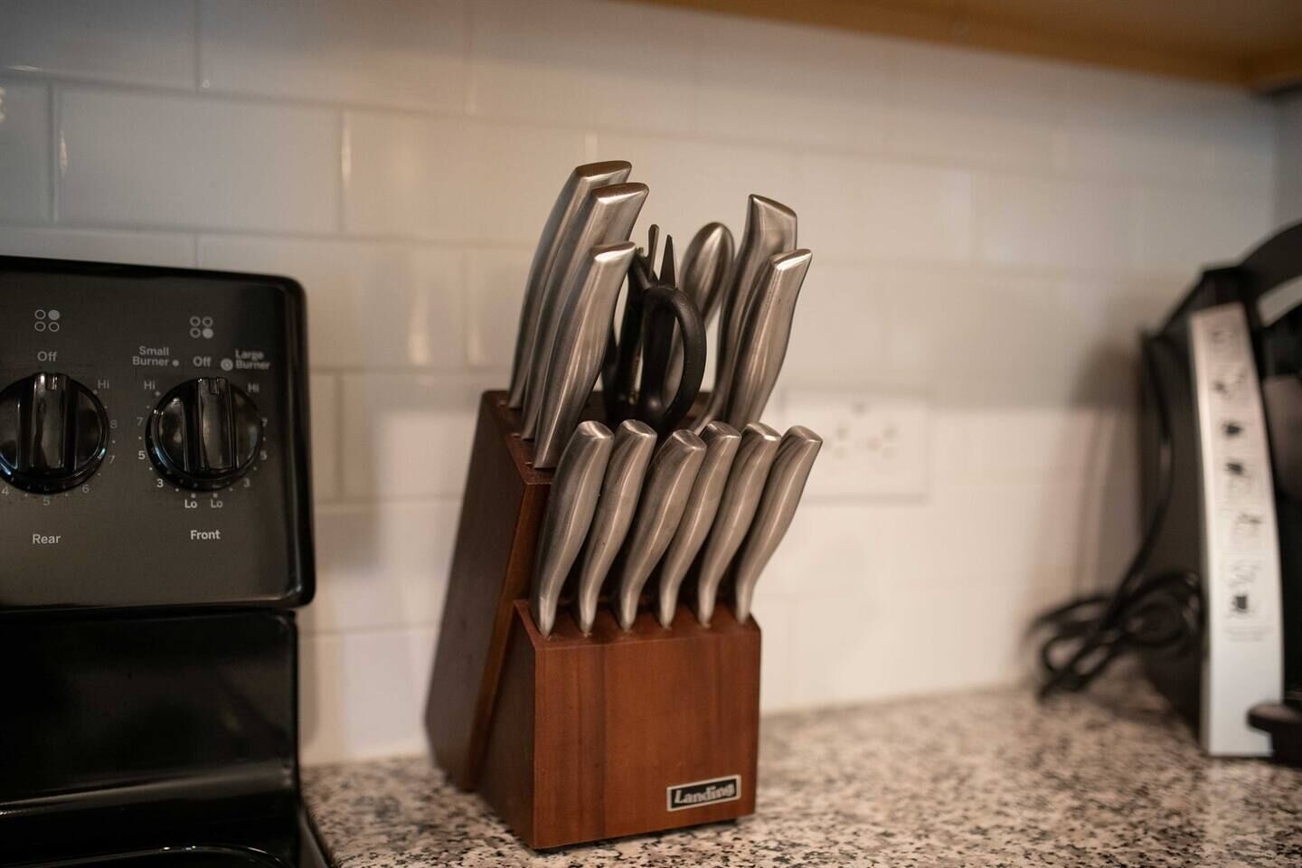 A kitchen with a stove and a knife holder on the counter.