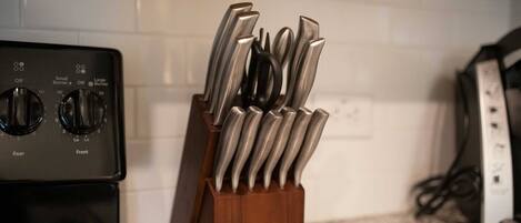 A kitchen with a stove and a knife holder on the counter.