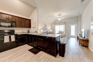 A kitchen with dark wood cabinets, a built-in microwave, and a large island with a sink.
