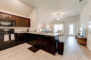 A modern kitchen with dark wood cabinets, a granite countertop, and stainless steel appliances.