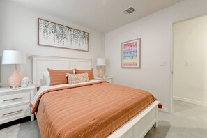 Ein Schlafzimmer mit einem Bett, zwei Nachttischen, einem Wandbild und einer Tür.