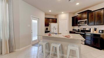 A modern kitchen with dark wood cabinets, a central island with stools, and a white countertop.