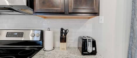 Une cuisine équipée d’une cuisinière en acier inoxydable, d’un grille-pain et d’un bloc à couteaux posé sur le plan de travail.