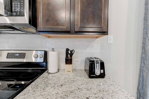 A kitchen with a stainless steel stove, a toaster, and a knife block on the countertop.