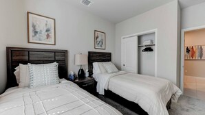A hotel room with two beds, a nightstand with a lamp, and artwork on the walls. - Brand New Home in Temple (Temple)