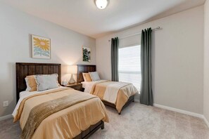 A bedroom with two beds, a nightstand, a lamp, and a window with curtains. - Brand New Home in Temple (Temple)