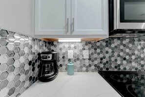 A kitchen with hexagonal tile backsplash, a coffee maker, and a teal water dispenser.
