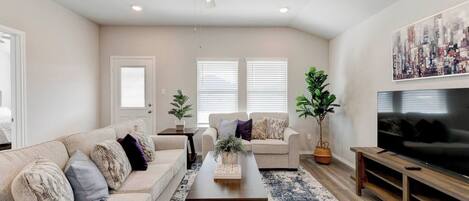A living room with a sofa, coffee table, TV, and ceiling fan.