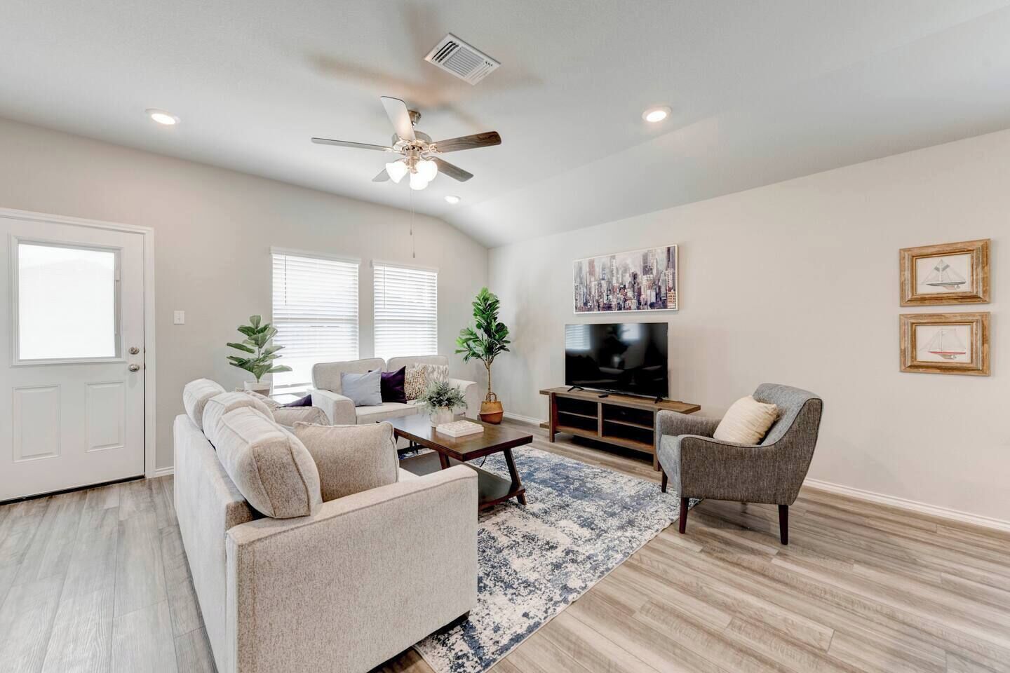 A living room with a sofa, armchair, coffee table, TV, and artwork on the wall.