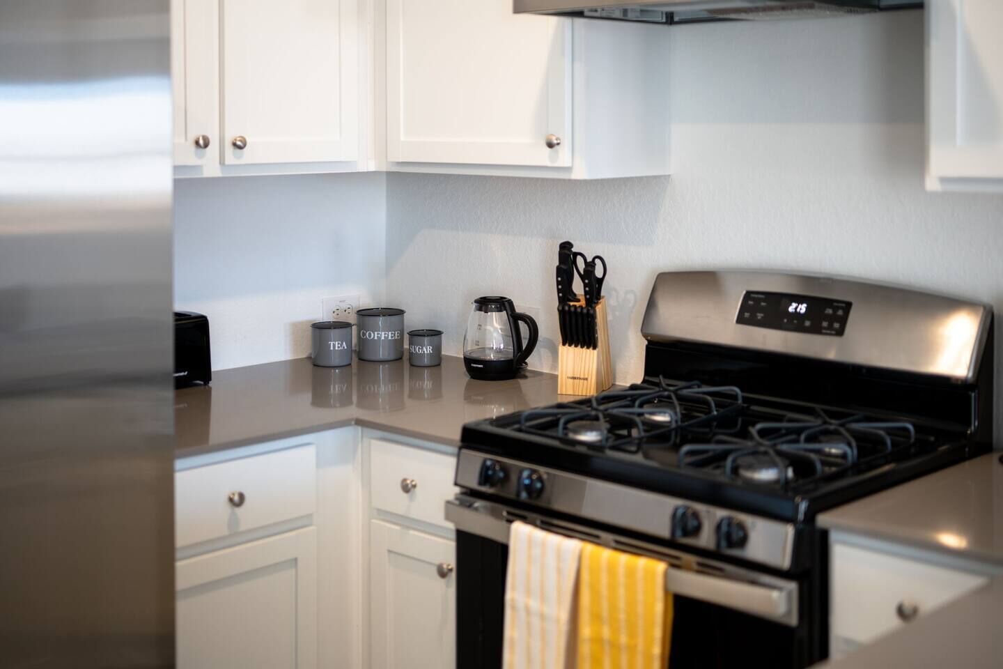 A kitchen with a stainless steel stove, white cabinets, and a coffee maker on the counter.