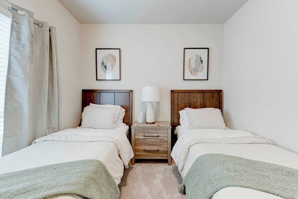 Une chambre double avec deux lits, une table de chevet avec une lampe et des œuvres d’art accrochées aux murs.