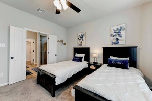 A bedroom with two beds, a ceiling fan, and artwork on the walls. - 4 Bedroom House in North Point (Temple)