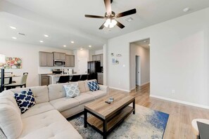 A modern living room with a sectional sofa, a wooden coffee table, and a ceiling fan. - 4 Bedroom House in North Point (Temple)