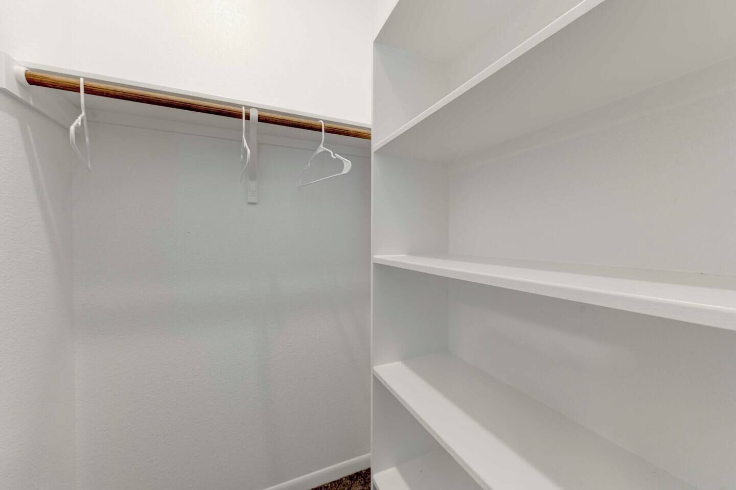 Un placard aux murs blancs, aux moulures en bois et aux étagères vides.