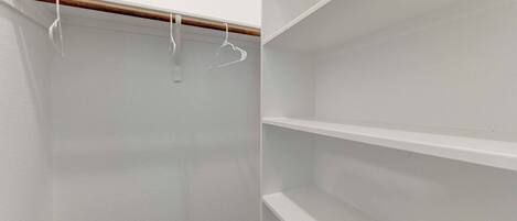 Un placard aux murs blancs, aux moulures en bois et aux étagères vides.