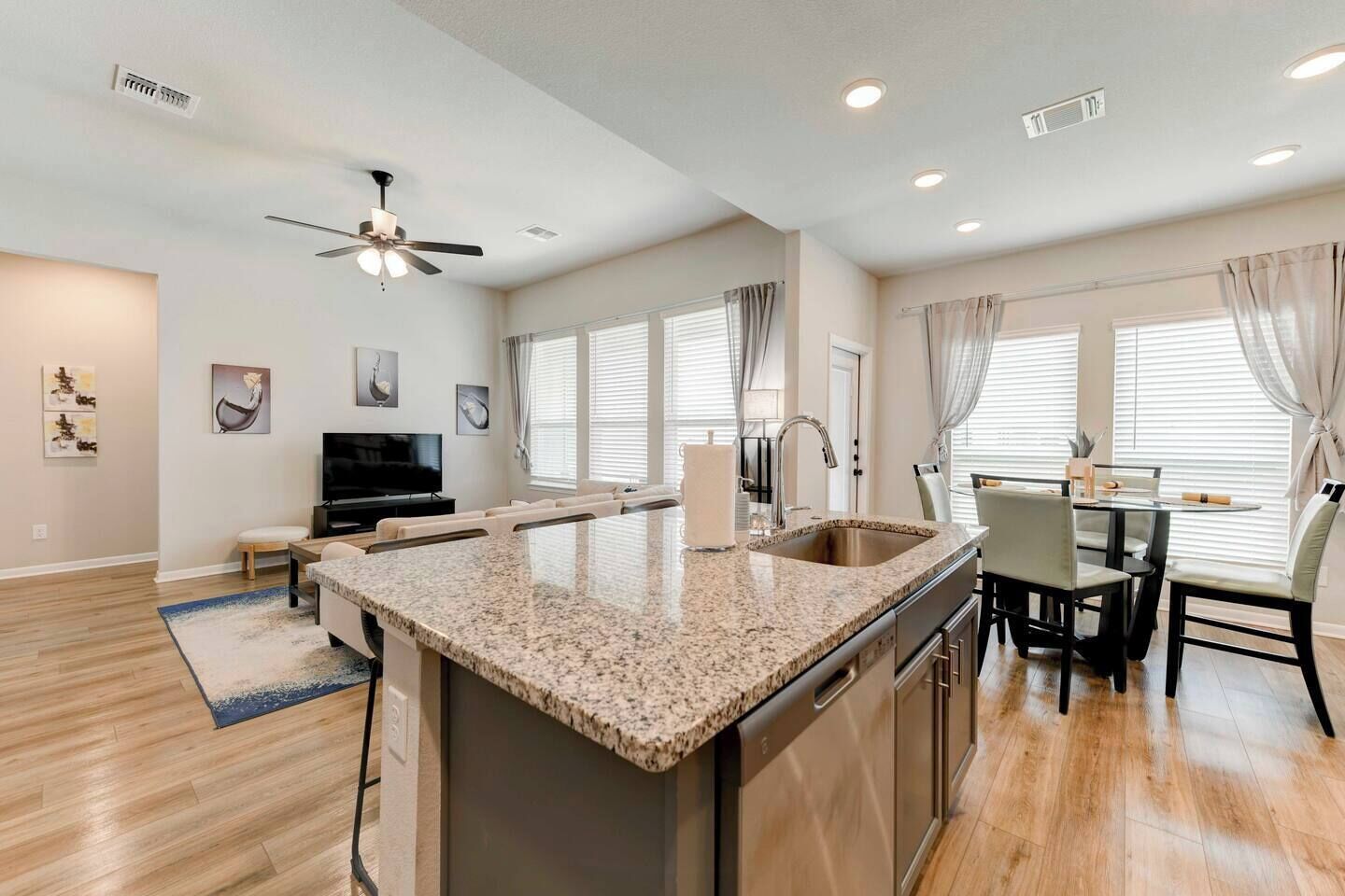 A modern kitchen with granite countertops, a built-in dishwasher, and a dining area with a table and chairs.