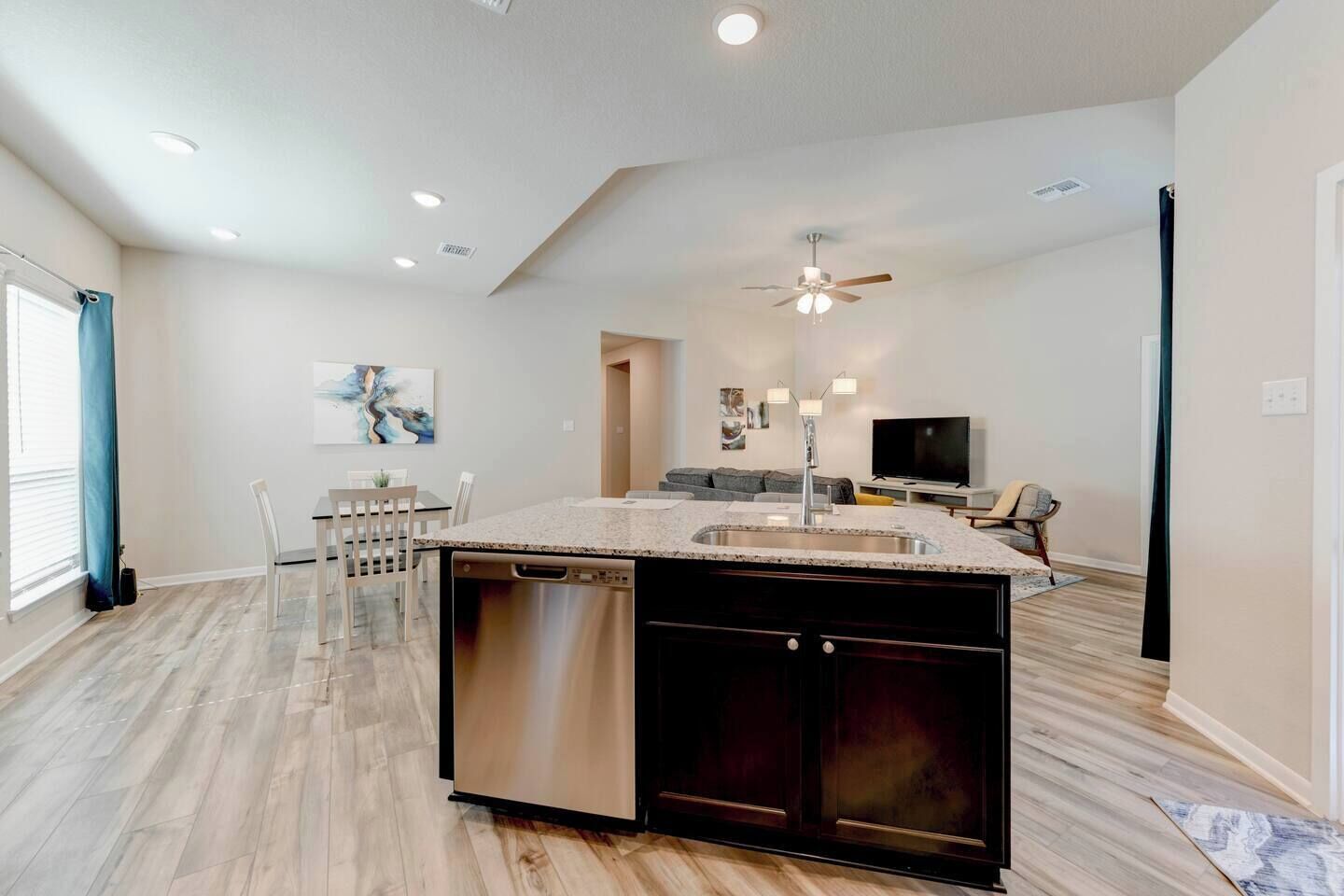 A modern kitchen with a central island, built-in dishwasher, and a ceiling fan.