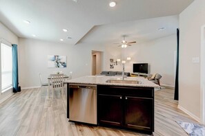A modern kitchen with a central island, built-in dishwasher, and a ceiling fan.