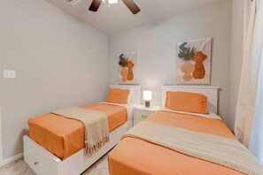 A bedroom with two beds, a ceiling fan, and artwork on the walls.