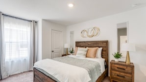 Un dormitorio con una cama de madera, una mesita de noche, un espejo y una ventana con cortinas.