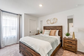 Un dormitorio con una cama de madera, una mesita de noche, un espejo y una ventana con cortinas.