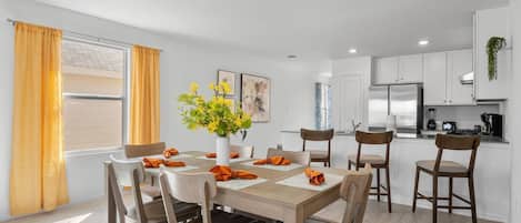 A modern kitchen with white cabinets, a built-in oven, and a stainless steel refrigerator.