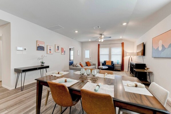A modern living room with a dining area, a sofa set, and a television.