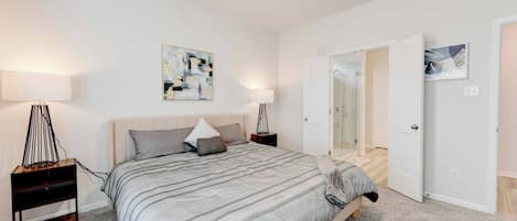Une chambre à coucher avec un lit, des tables de chevet, un ventilateur de plafond et des œuvres d’art accrochées aux murs.