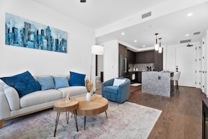 A modern living room with a sofa, coffee table, and a cityscape painting.