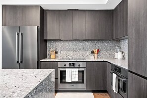 Una cocina moderna con gabinetes de madera oscura, un refrigerador de acero inoxidable, un horno Bosch y una encimera de granito.