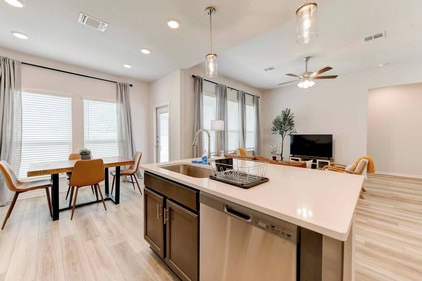 A modern kitchen with a central island, built-in appliances, and a dining area with a table and chairs.