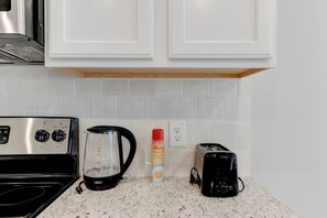 A kitchen with a stove, coffee maker, and toaster. - Spacious South Temple Home with 5 Bed (Temple)